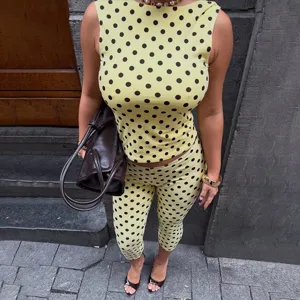 Gedetailleerd uitzicht op stijlvolle dameset met gele polkadot mouwloze top en capribroek.