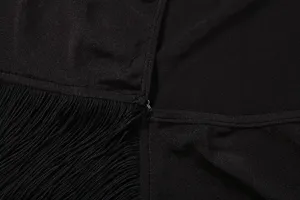 Détail d'un haut à manches longues et franges noires avec texture et belle finition.