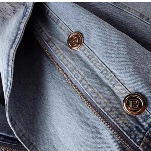 Gedetailleerd opname van korte dames denim jas met metalen knopen, rits en bontkraag.