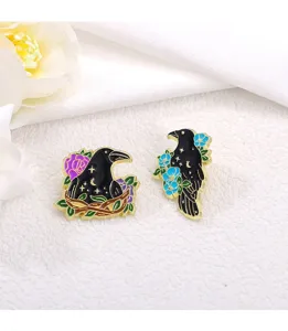 Close-up detail of dark style crow enamel pins with flowers and starry elements for clothing.
