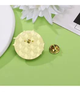 Dettaglio in primo piano del retro della spilla dorata con motivo geometrico e chiusura a farfalla.