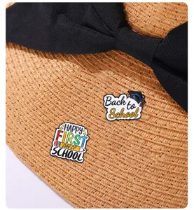 Gros plan et détail de jolies broches en émail sur le thème de l'école sur chapeau.