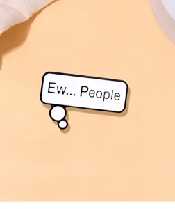 Detail shot of enamel brooch with English speech bubble text design, sleek metallic finish.