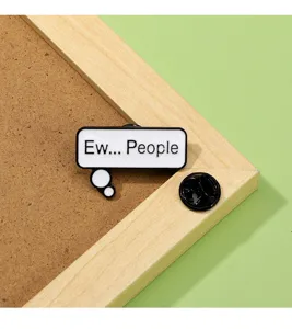 Close-up detail of English slogan speech bubble enamel lapel pin, alloy clothing accessory.