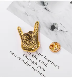 Gold rock hand sign alloy brooch detail shot, vintage distressed finish metal lapel pin badge.