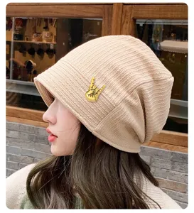 Close-up detail of the vintage gold hand gesture brooch pin on a stylish knitted beanie hat.