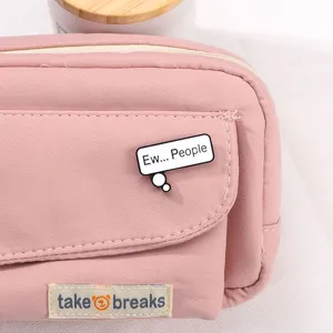 Pink canvas pencil case with metal badge and cute fabric label, stylish and practical stationery pouch.