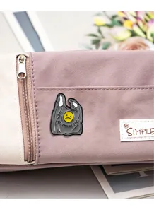 Close-up detail shot of the creative sad smiley plastic bag enamel pin on canvas bag.