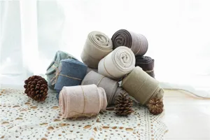 Vue détaillée de collants en coton côtelés roulés de différentes couleurs sur table en dentelle.