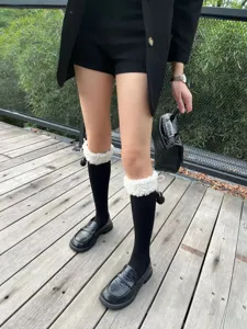 Women cute black slouch socks with white fleece fluffy cuff and cute pompom design for autumn.
