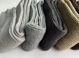 Close-up detail of cozy knit slouch socks in assorted neutral colors, soft ribbed texture.