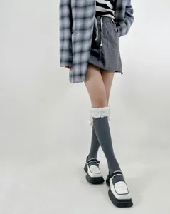 Women's autumn winter warm cotton cable knit calf socks with fluffy pom-pom cuffs, detail shot.