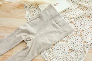 Gros plan détaillé des collants côtelés couleur avoine, montrant un tricot texturé.