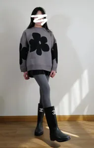 Dettaglio di collant invernali grigi opachi a vita alta abbinati a maglione floreale e stivali.