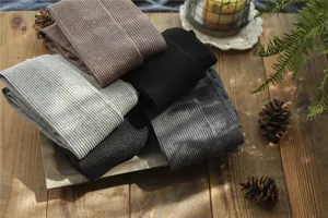 Detailed view of women's autumn winter ribbed cotton pantyhose stacked on wooden background.