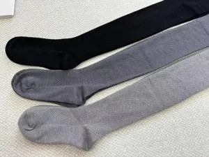 Detailed view of winter warm knitted tights with wave texture in classic grey and black colors.