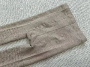 Close-up detail shot of women's warm knitted ribbed tights in light beige color.