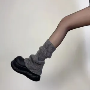 Scaldamuscoli in maglia grigia da donna, comode ghette invernali e calze presentate sulla gamba.