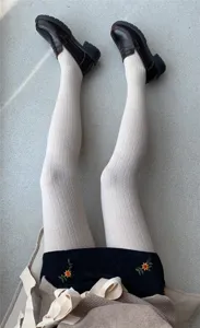 Vista detallada de medias de punto crema con textura, combinadas con mocasines marrones.