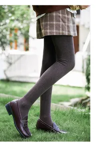 Close-up detail of thermal fleece lined ribbed tights in coffee brown, worn on outdoor grass.