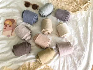 Détail de collants côtelés roulés de diverses teintes, disposés dans un cadre de vie chaleureux.