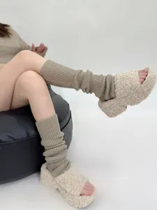 Cozy knitted leg warmers detail view, soft textured fabric paired with comfortable fluffy slippers.