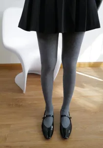 Primo piano dettagliato di collant grigi a coste spesse a vita alta con scarpe nere.