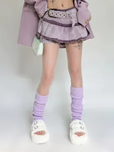 Detailed view of fashionable purple knitted leg warmers styled with fluffy sandals and skirt.