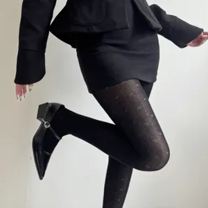 Detail view of black tights with retro jacquard bow design for women's autumn style.