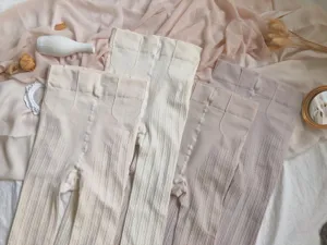 Vista detallada de medias de punto grueso en tonos crema con una textura fina acanalada.