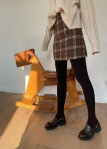 Detailed view of cozy winter outfit featuring fleece-lined tights and plaid skirt.