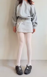 Cozy autumn winter grey sweatshirt mini skirt set paired with white tights and casual shoes.