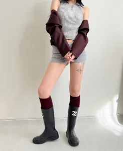 Detail shot of ribbed knit sleeveless top and shorts outfit paired with stylish rain boots.