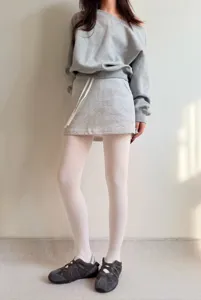 Detail view showing white opaque tights paired with grey sweatshirt and skirt for a stylish look.