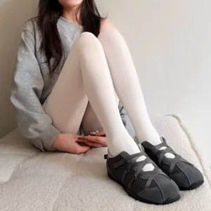 Detailed shot of women white tights styled with dark grey crossover strap casual shoes.
