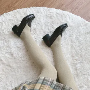 Close-up detail of warm oatmeal vertical striped tights paired with vintage loafers and skirt.