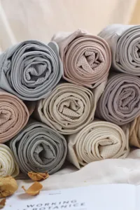 Close-up detail of rolled women tights and leggings in assorted soft neutral colors, textured fabric.