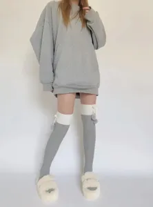 Vue détaillée de chaussettes hautes en tricot gris contrasté avec de jolis nœuds pompons.