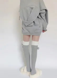 Vue détaillée de chaussettes hautes grises à pompons pelucheux, maille douce et confortable.