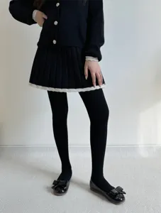Detail shot of women's black ribbed thermal pantyhose styled with chic autumn winter outfit.
