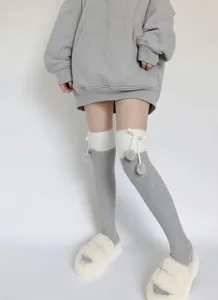 Chaussettes hautes grises et blanches douillettes avec des pompons en peluche et jolis nœuds.
