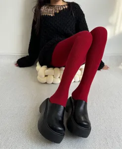 Detail view of women's warm winter ribbed wine red pantyhose paired with black platform shoes.