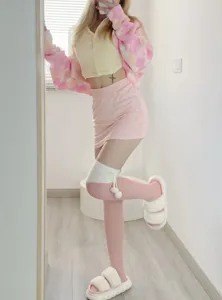 Vue détaillée de chaussettes hautes en peluche rose et blanche avec des pompons.