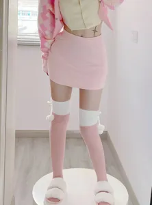 Vue détaillée de chaussettes hautes roses en peluche douce avec des pompons mignons.