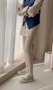 Detail view of cream flesh-colored high-waist pantyhose showing legs and slim fit effect.