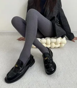 Close-up detail shot of smoky grey ribbed knit tights paired with black loafers.