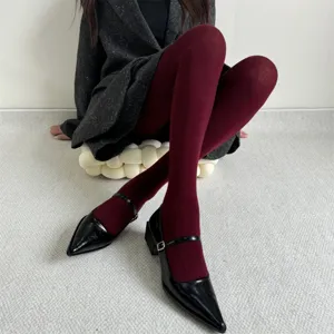 Gros plan détaillé sur des collants bordeaux doublés thermiques portés avec des escarpins.