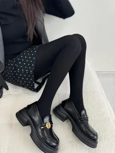 Detailed view of women's black cable knit tights and loafers, showcasing winter legwear style.