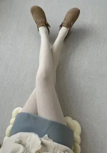 Close-up detail shot of retro knit cable pantyhose in neutral tone, worn with cozy shoes.