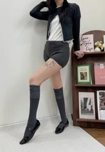 Cozy knit cardigan shorts and over-the-knee socks detail shot in indoor lifestyle setting.